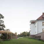 Bočný pohľad na historickú vilu na pražských Vinohradoch s novým záhradným prístreškom a zeleným trávnikom.