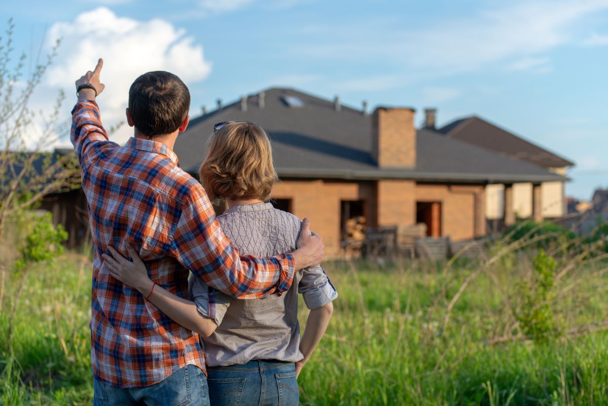 Muž a žena stoja na lúke pri rodinných domoch.