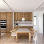 Elegantný jedálenský priestor s nadčasovým dreveným stolom a stoličkami pri drevenej kuchynskej linke.