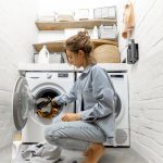 Mladá žena nakladá v práčovni práčku špinavou bielizňou.