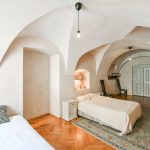 Spálňa s klenutým stropom, dvoma posteľami a historickým zariadením v zrekonštruovanej fare v Chudeniciach.