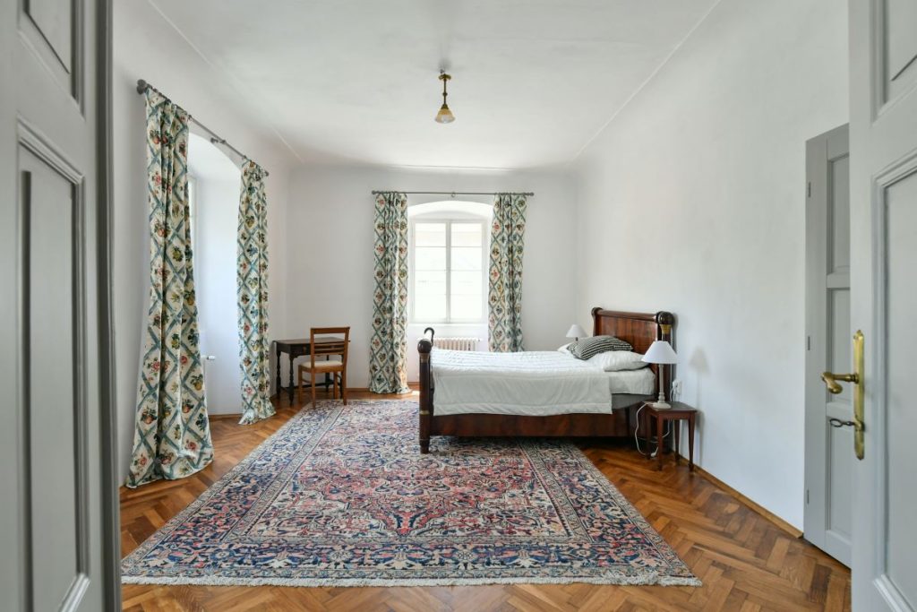 Spálňa s klenutým stropom a priamym vstupom do kúpeľne v zrekonštruovanej fare v Chudeniciach.