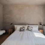 Spálňa v dovolenkovom dome na ibize s posteľou, lavicou a nočnými stolíkmi.