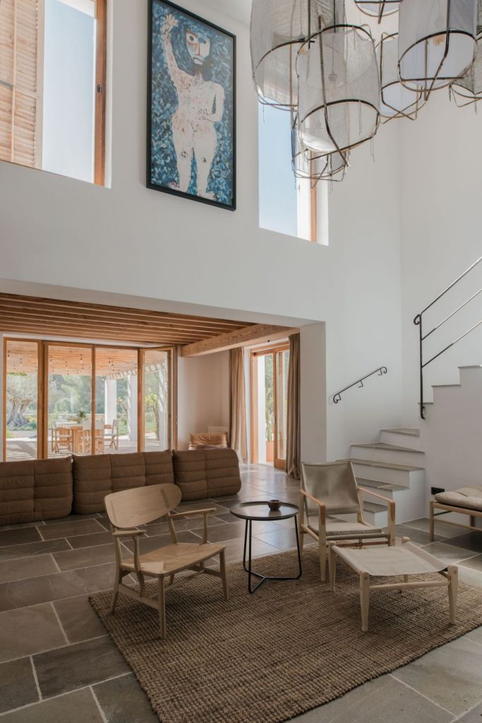 Vnútorný priestor s vysokým stropom, veľkými oknami, minimalistickým sedacím nábytkom a umeleckým dielom.