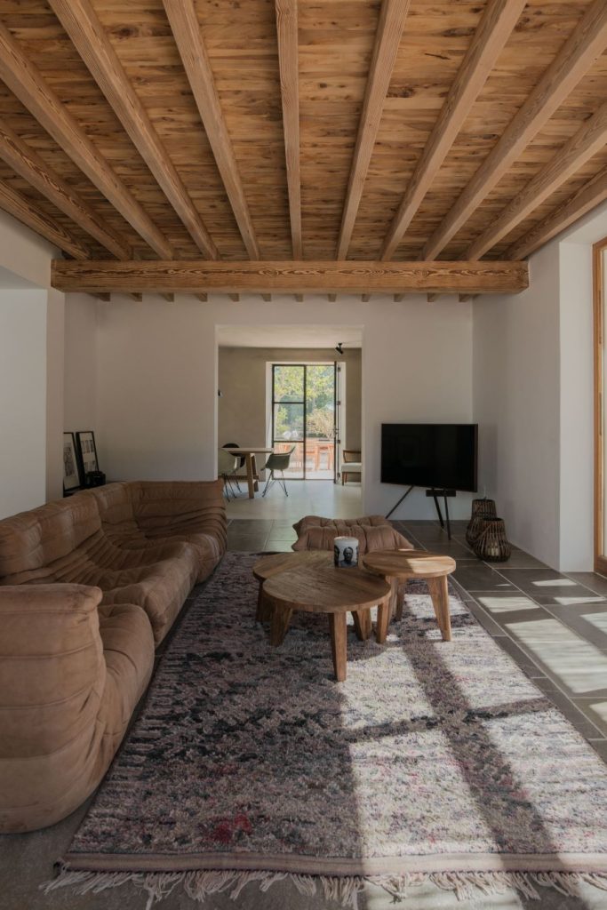 Obývacia izba s dreveným trámovým stropom, pohodlnou sedačkou a dreveným konferenčným stolíkom.