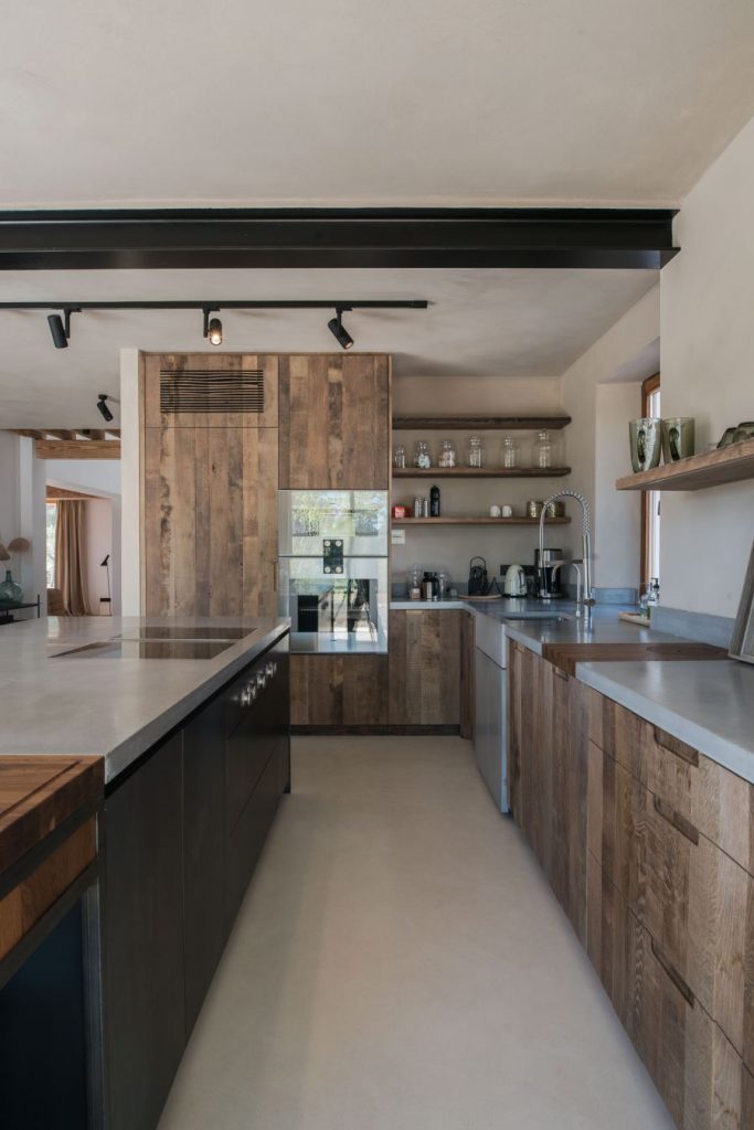 Moderná kuchyňa s drevenými rustikálnymi skrinkami a antikorovými pracovnými plochami.