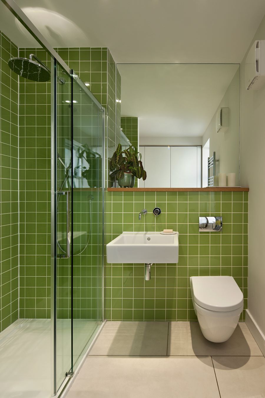 Kúpeľňa so zelenými kachličkami, sprchovým kútom a bielym sanitárnym zariadením.