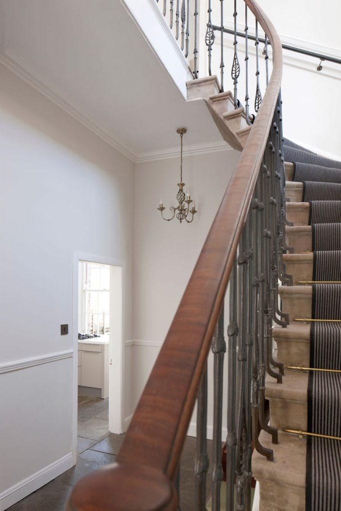 Detail schodiska s dreveným zábradlím a dekoratívnymi prvkami v zrekonštruovanom historickom dome.