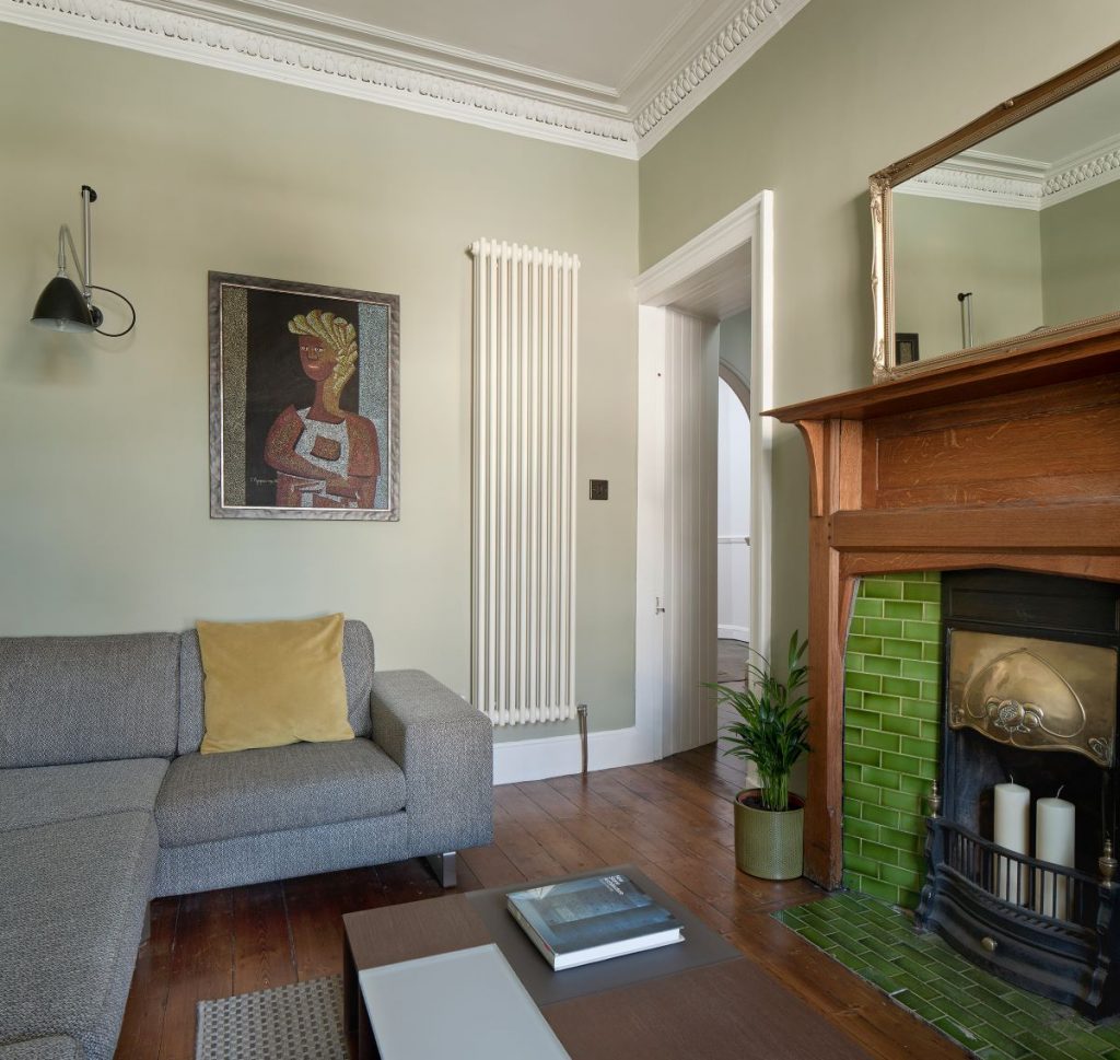Štýlová obývacia izba s pohovkou, krbom a moderným obrazom na stene.