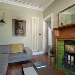 Štýlová obývacia izba s pohovkou, krbom a moderným obrazom na stene.