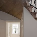 Detail schodiska a chodby s výhľadom na svetlú miestnosť v zrekonštruovanom historickom dome.