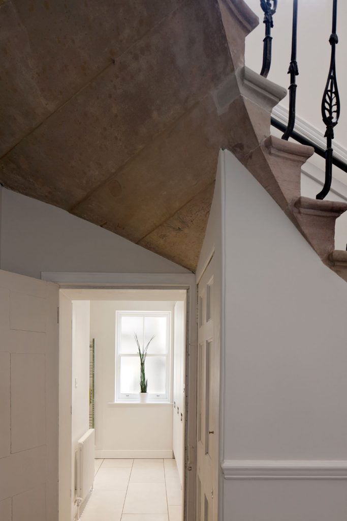 Detail schodiska a chodby s výhľadom na svetlú miestnosť v zrekonštruovanom historickom dome.