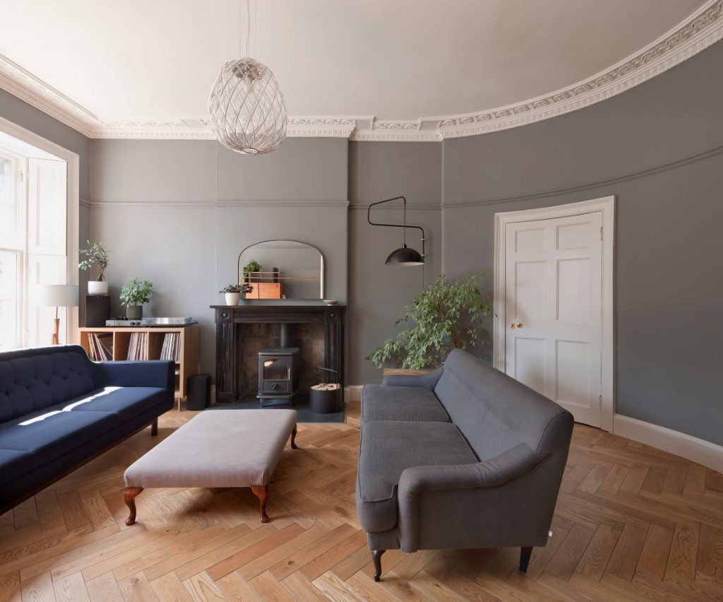 Priestranná obývacia izba s moderným nábytkom a krbom v zrekonštruovanom historickom dome.