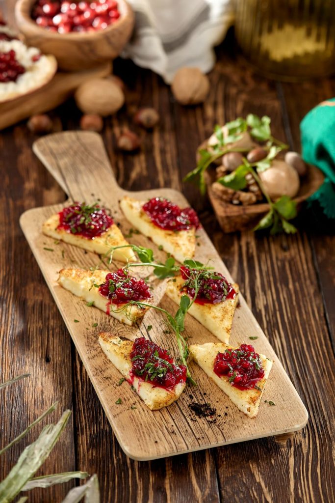 Grilované trojuholníky syra so salsou a bylinkami na drevenej doske.