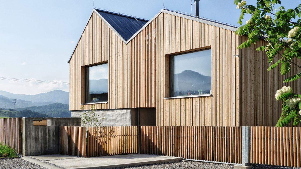 Moderný drevený dom v minimalistickom dizajne s veľkými oknami a výhľadom na hory.