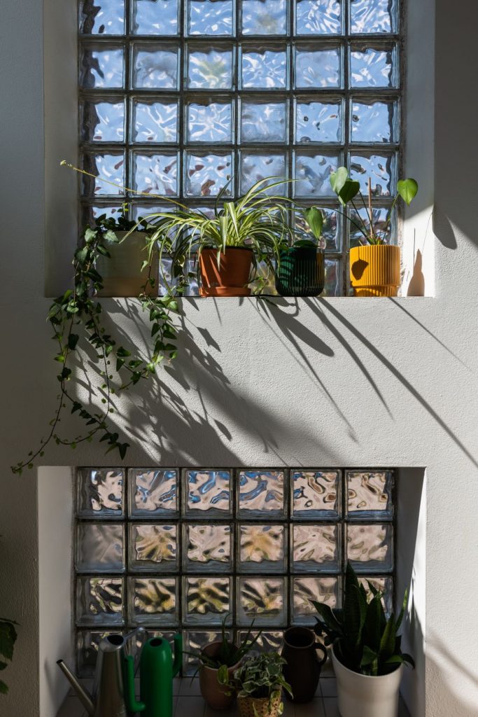 Okno s murovanou policou s interIérovými kvetinami.