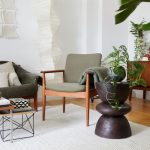 Časť obývacej izby so sedačkou a kreslom v šalviovej farbe, malými stolíkmi a retro nábytkom.