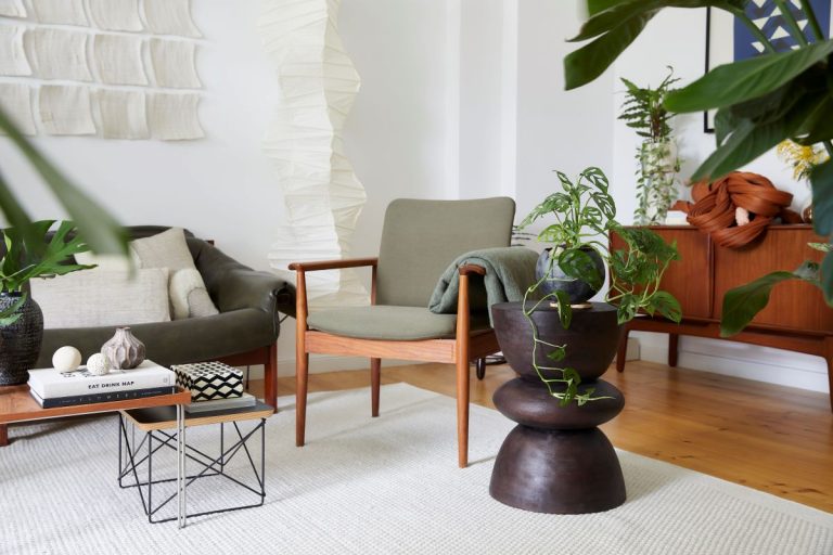 Časť obývacej izby so sedačkou a kreslom v šalviovej farbe, malými stolíkmi a retro nábytkom.