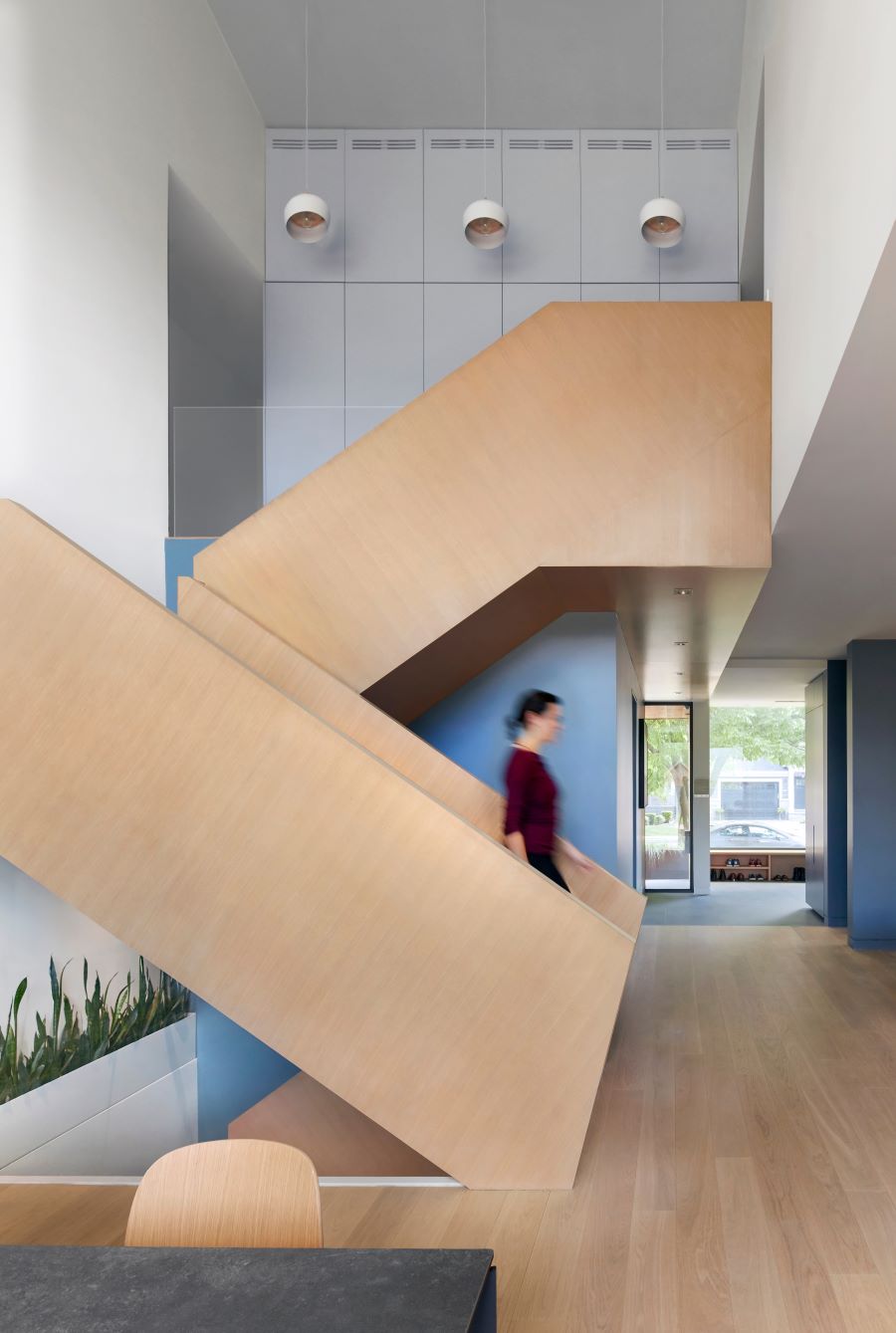 Nožnicová konfigurácia schodiska tvorí dynamickú geometrickú kompozíciu, oživenú pohybom postáv.