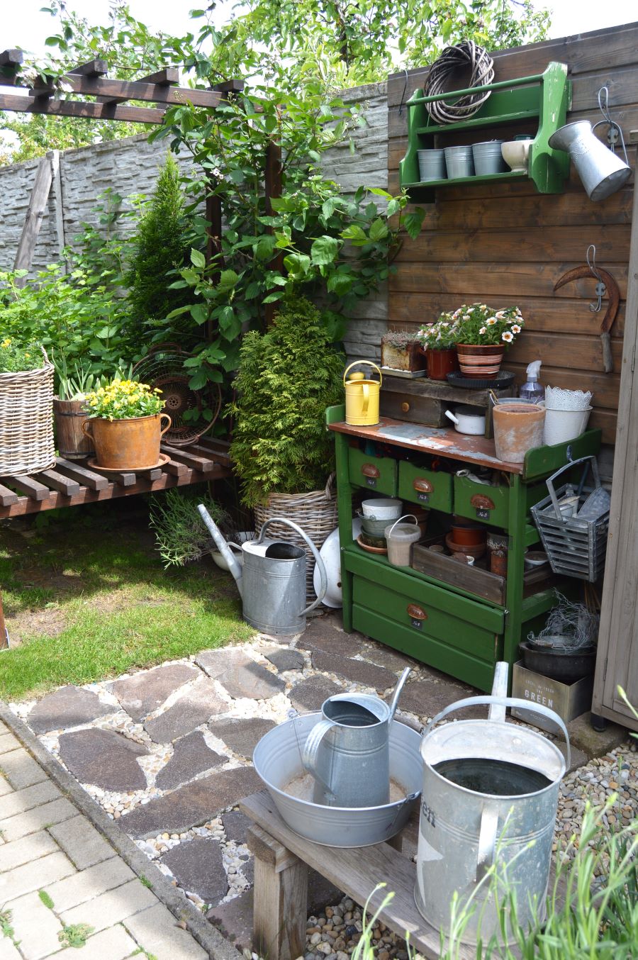 Záhradný priestor s rastlinami, záhradným nábytkom a rustikálnym náradím
