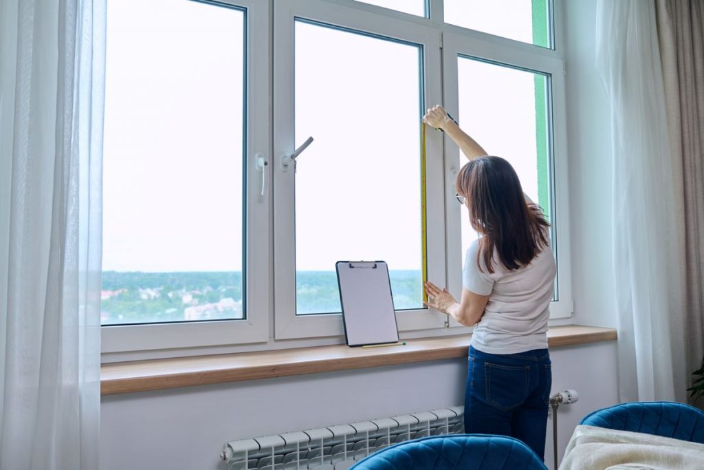 Žena meria rozmery okna.