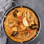 Paella valeciana s morskými plodmi v hrnci.