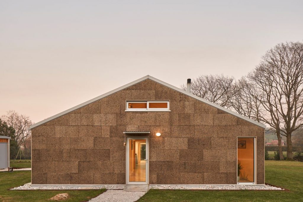 Predná strana moderného jednopodlažného domu so stenami z laminovaného dreva v minimalistickom dizajne.