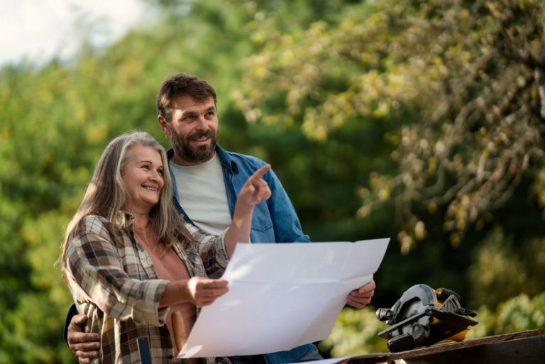 Halfpoint/iStock Starší muž a žena s plánom v ruke sa dívajú na okolie.