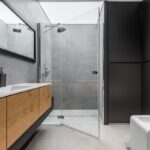 Moderná kúpeľňa s walk-in sprchovým kútom, umývadlom a drevenými skrinkami.