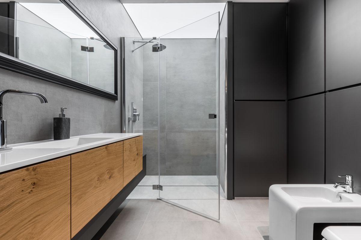 Moderná kúpeľňa s walk-in sprchovým kútom, umývadlom a drevenými skrinkami.