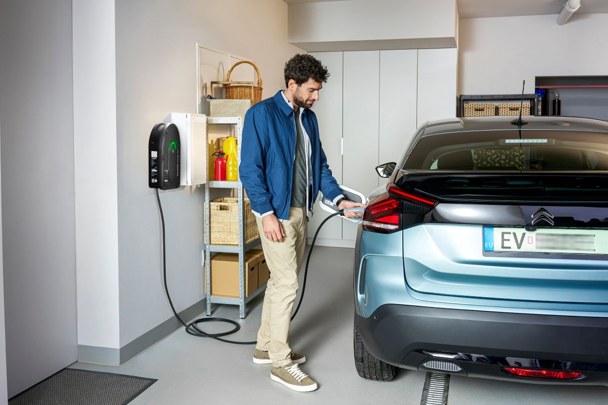 Muž pri nabíjaní elektroauta v garáži.