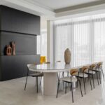 Luxusná minimalistická jedálenská časť s oválnym stolom a modernými sochami.