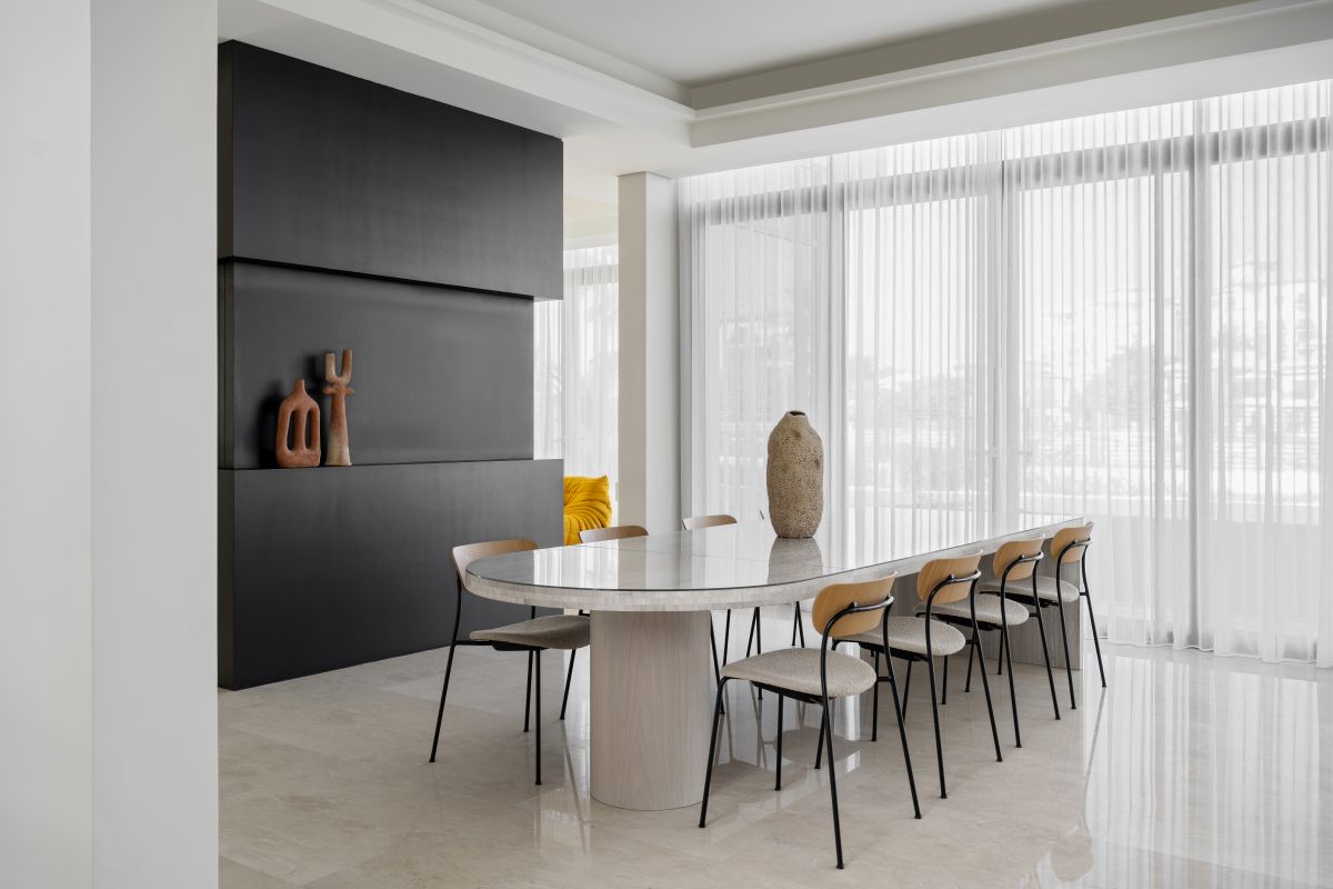 Luxusná minimalistická jedálenská časť s oválnym stolom a modernými sochami.