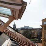 Výhľad zo strešného okna na strechy mesta s výhľadom na Bratislavský hrad.