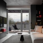 Moderný obývací priestor s minimalistickým dizajnom a veľkými sklenenými dverami na balkón.