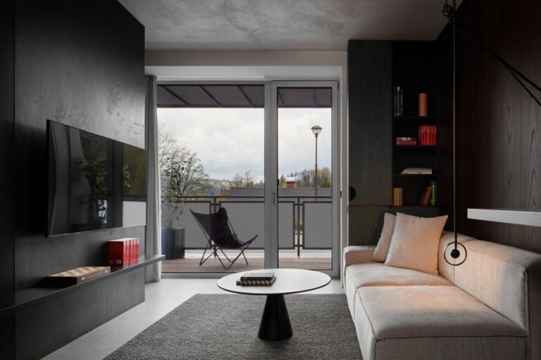 Moderný obývací priestor s minimalistickým dizajnom a veľkými sklenenými dverami na balkón.