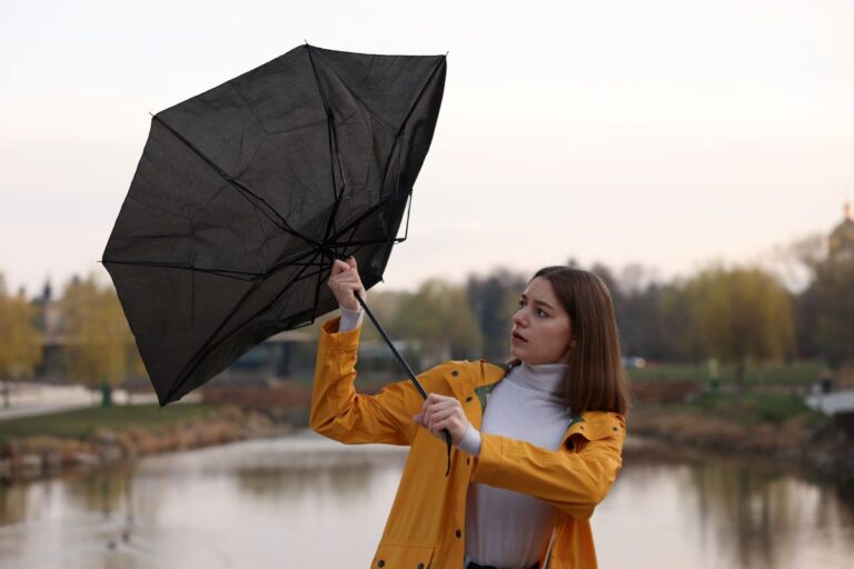 Mladá žena s polámaným dáždnikom v ruke.