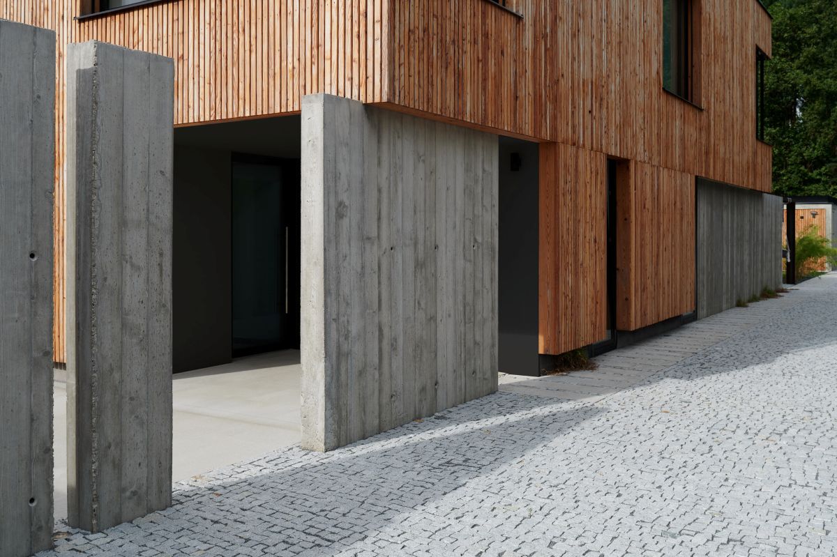 Architekti stavili na pevný betón a drevo, ktoré stavbe dodáva hrejivosť a prírodnosť.