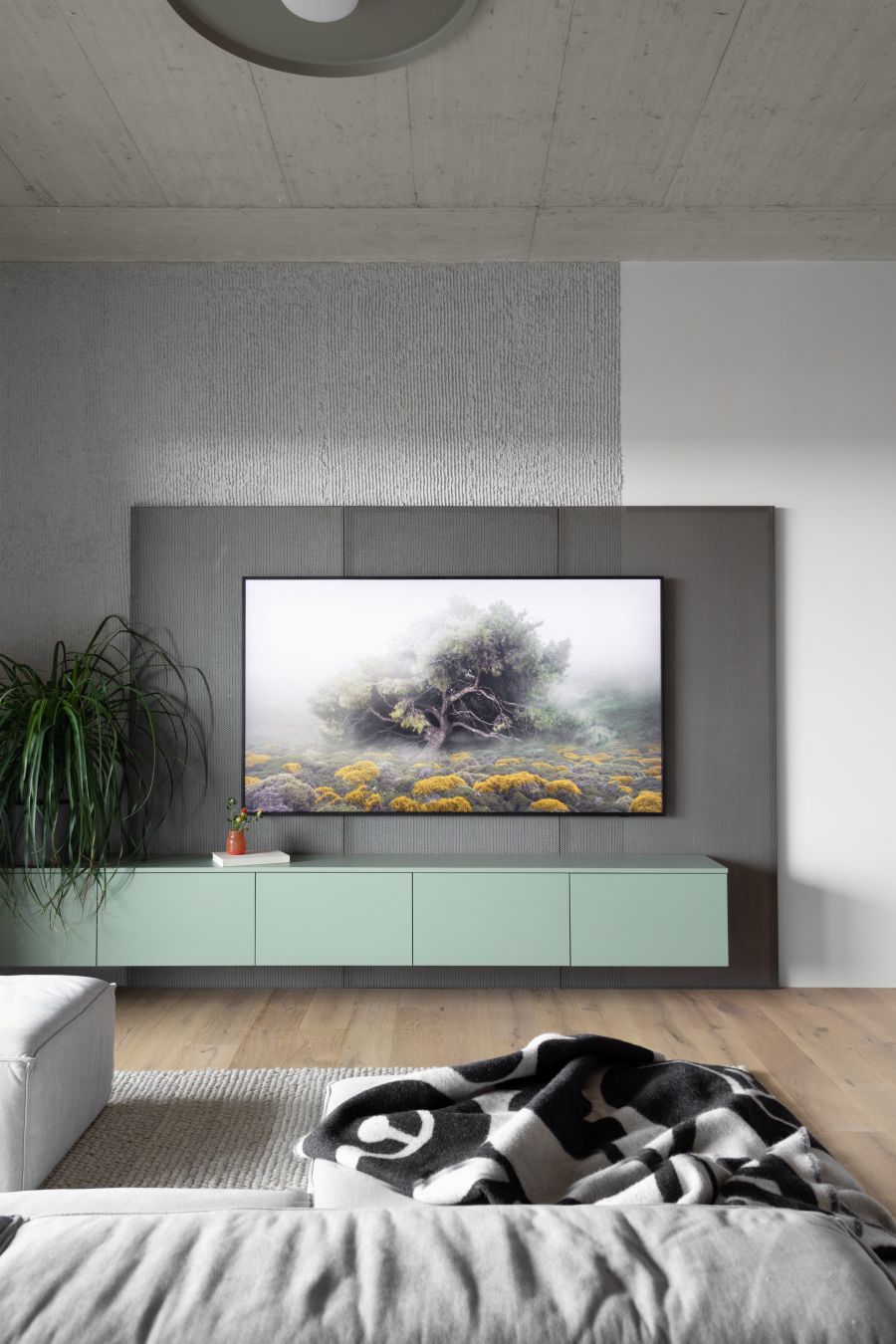 Obývačka s moderným nábytkom a veľkým televízorom na stene.