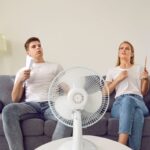 Mladý muž a žena sa ovievajú pri ventilátore.