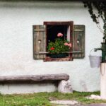 Drevená lavica pod oknom s muškátom