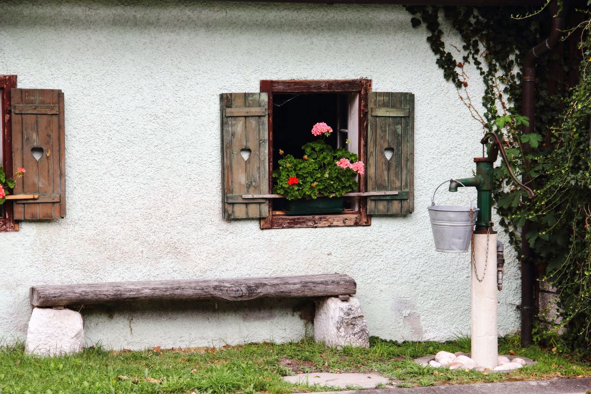 Drevená lavica pod oknom s muškátom