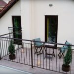 Drevený stôl a stoličky na balkóne rodinného domu.