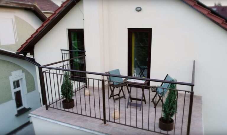 Drevený stôl a stoličky na balkóne rodinného domu.