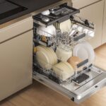 Otvorená umývačka riadu Whirlpool s riadom.