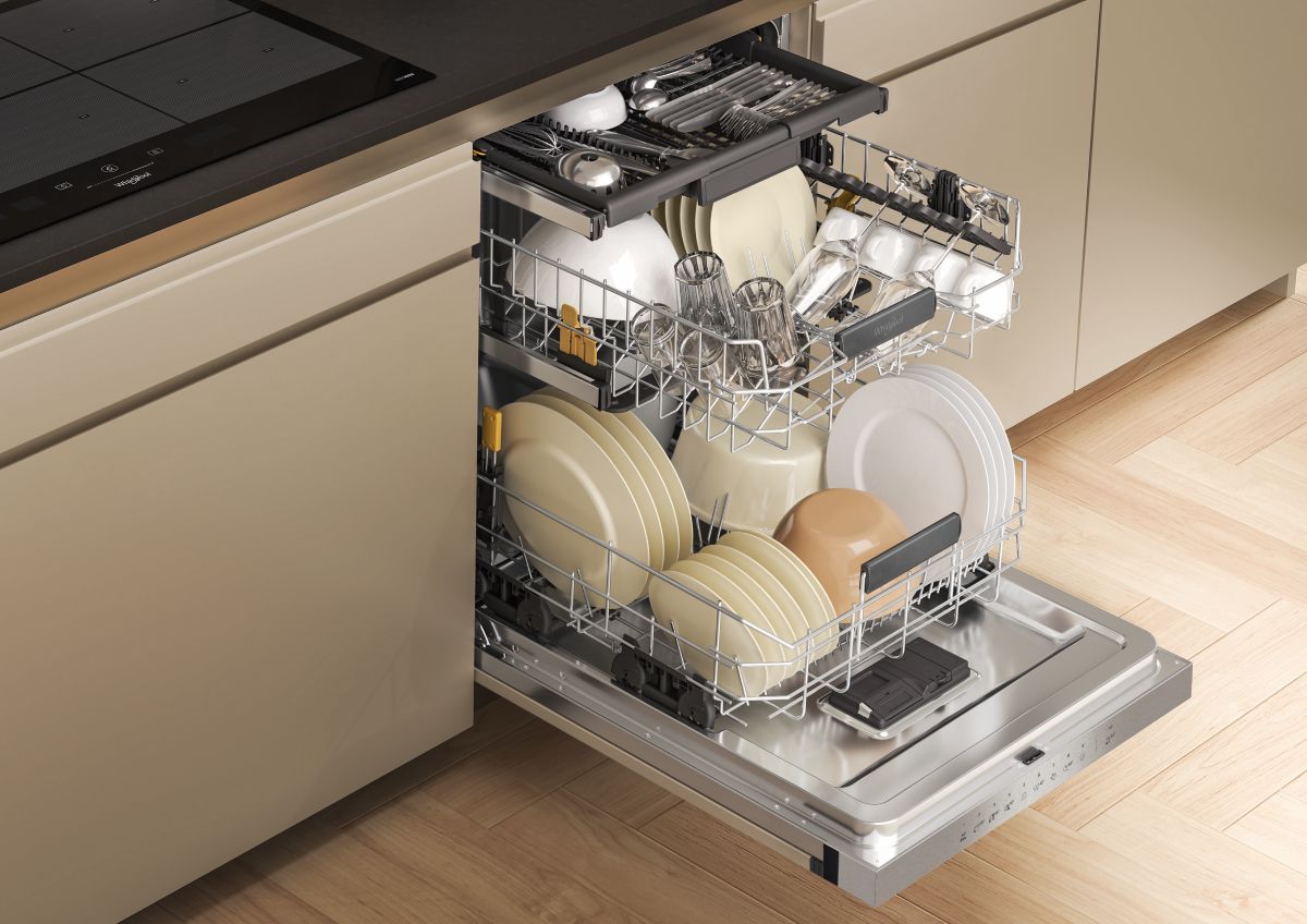 Otvorená umývačka riadu Whirlpool s riadom.