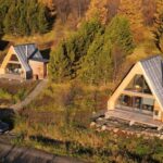 Tri tiny houses s áčkovým tvarom v prírode pod lesom.
