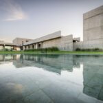 Bazén s betónovým domom s minimalistickou architektúrou.