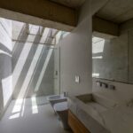 Kúpeľňa so svetlíkmi a pohľadom na sprchovací kút, bidet a umývadlo.