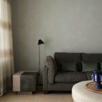 Detail interiéru s tmavosivou sedačkou a moderným bočným stolíkom.